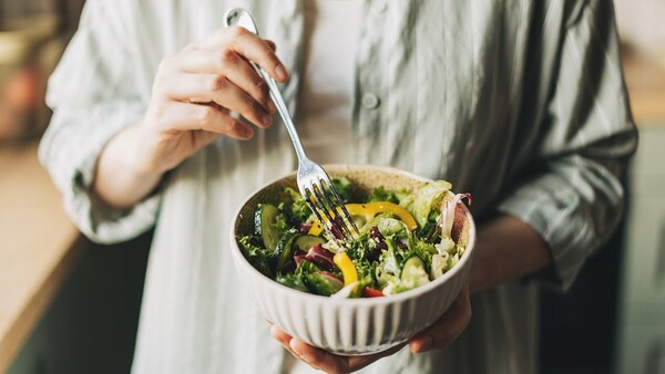 Person holding a bowl of salad in a relaxed home setting